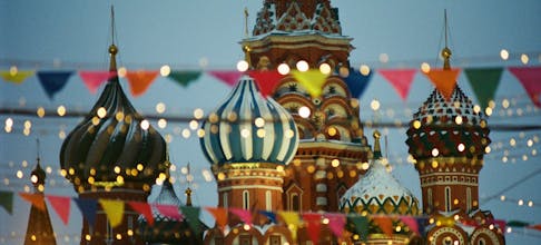 A vibrant view of St. Basil's Cathedral with festive flags and lights in Moscow, Russia.