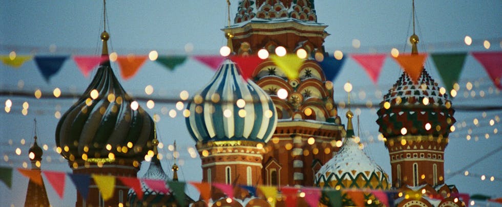 A vibrant view of St. Basil's Cathedral with festive flags and lights in Moscow, Russia.