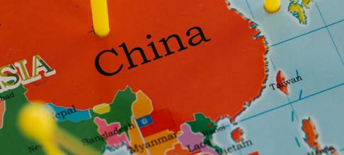Close-up of a map highlighting China with colorful pins and flags in Asia.