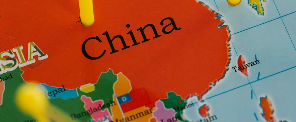 Close-up of a map highlighting China with colorful pins and flags in Asia.