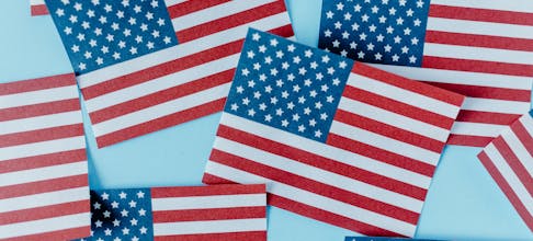 Multiple American flags on blue background symbolizing patriotism and Independence Day.