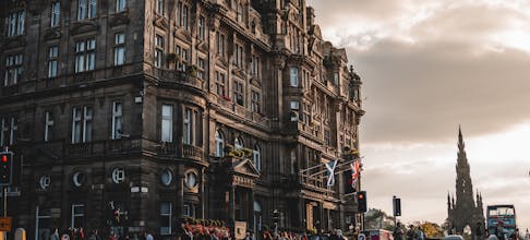 Scenic view of iconic Edinburgh architecture during sunset with people and traffic.