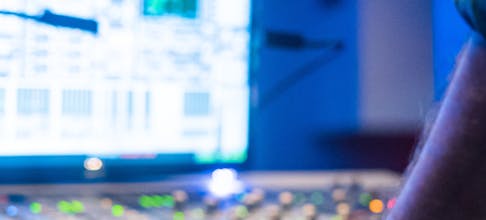 Unrecognizable man adjusting lever on modern control panel during performance in illuminated hall