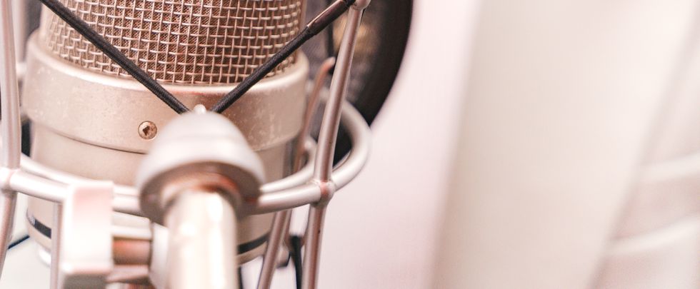 Woman recording music with a condenser microphone in a studio setting.